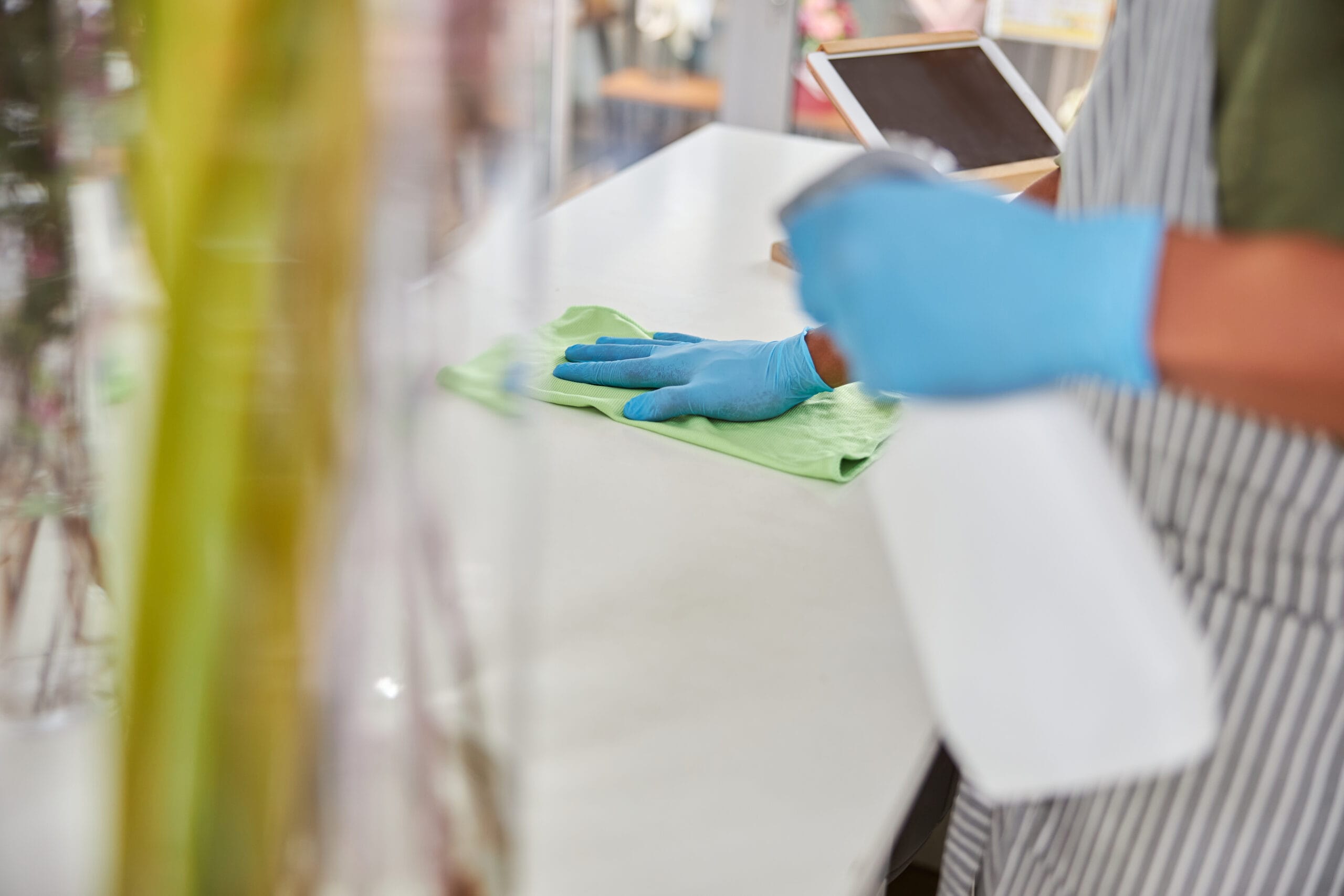 Top view cropped head close up of man in latex gloves doing desinfection in flower shop during quarantine